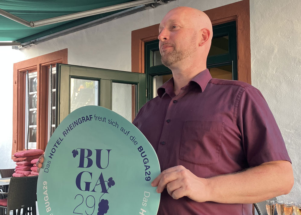 sliderimage-Uwe Girnstein präsentiert seinen BUGA-Sticker für das Hotel Rheingraf