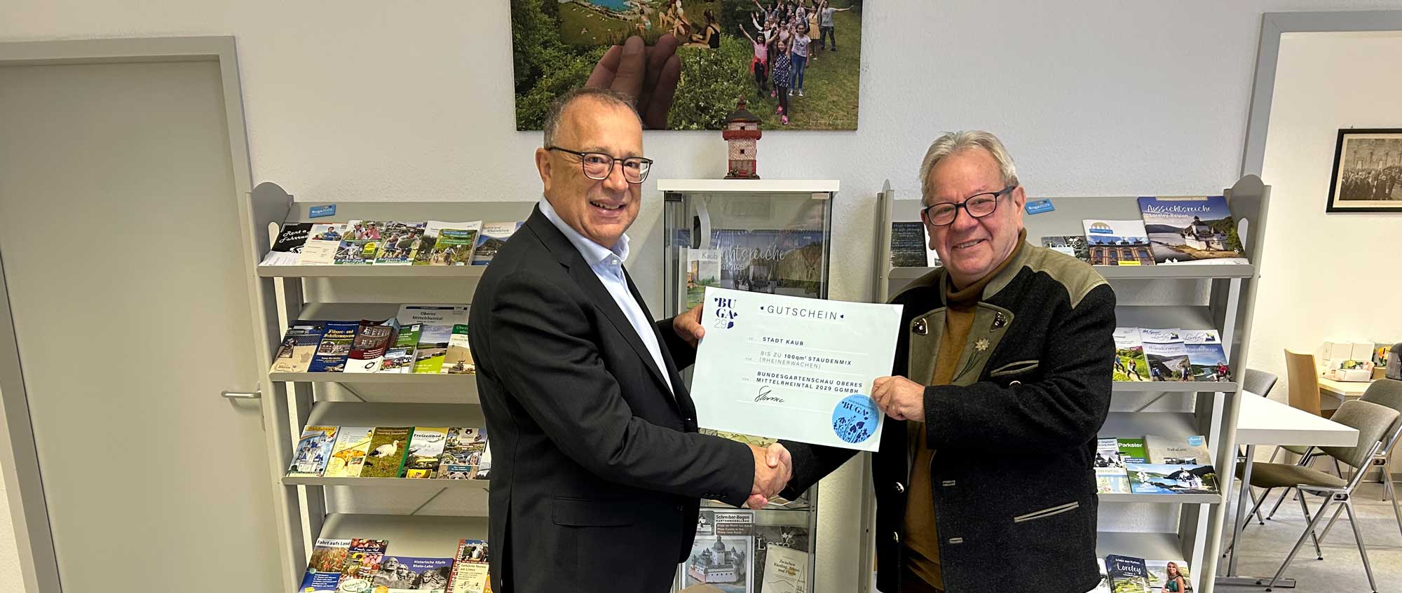 Ein Mann gibt einem anderen Mann einen großen Gutschein, beide lächeln in die Kamera