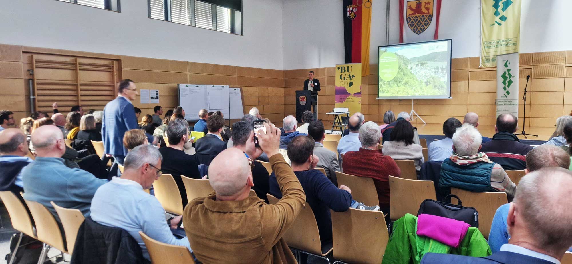 Der Vortragende Prof.-Dr.-Eckhard-Jedicke spricht vor einem interessierten Publikum in einer Sporthalle