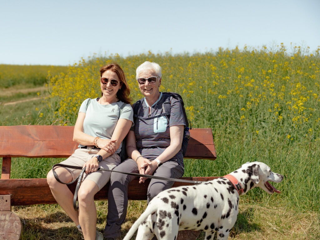 BUGA-Wanderevent Lorch am Rhein Zwei Frauen sitzen auf einer Bank im Feld, davor steht ein Dalmatiener