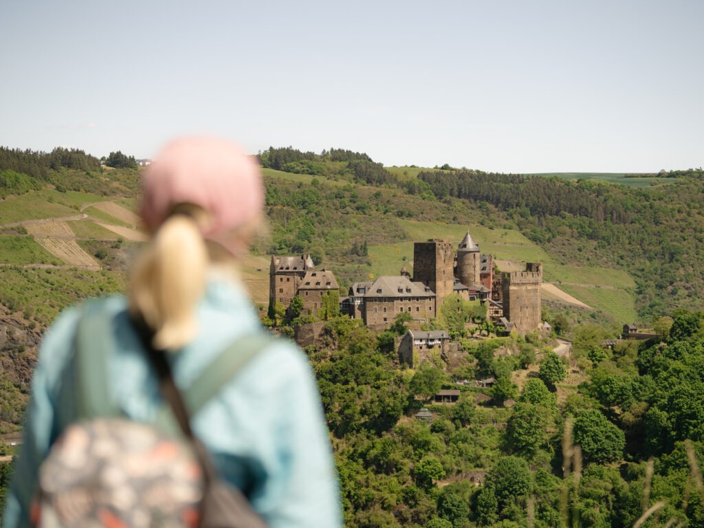 Aufruf zum Wettbewerb: „Werde BUGA-Erlebnispartner – Dein Produkt. Dein Erlebnis. Jetzt mitblühen!“ Eine Wanderin blickt auf eine Burg in der Ferne