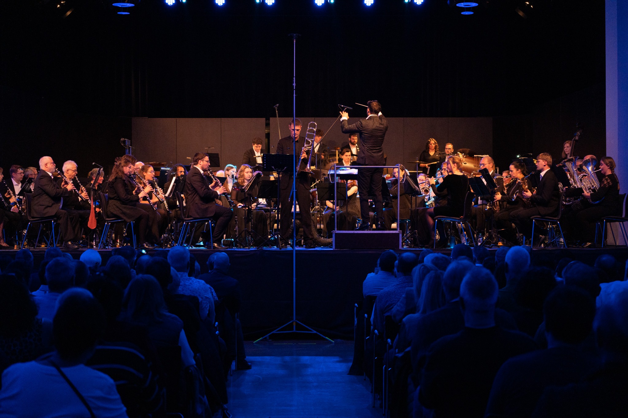Das BUGA-Orchester spielt in einem Konzertsaal, der mit blauer Beleuchtung in Szene gesetzt wird.
