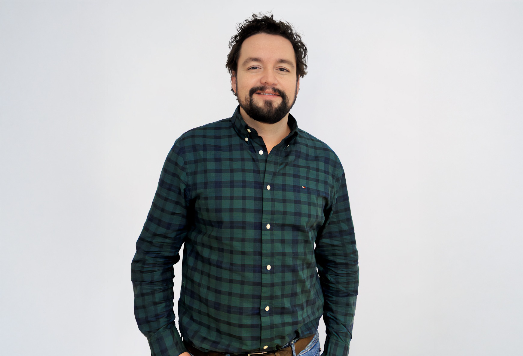 Mann mit dunklem, kariertem Hemd und braunem Gürtel vor weißem Hintergrund