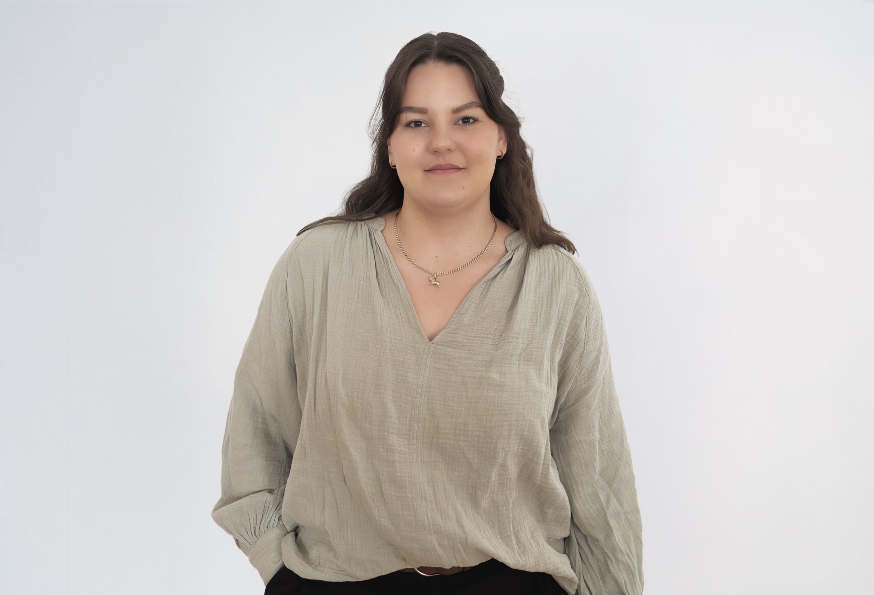 Eine braunhaarige Frau in einer grünen Bluse lächelt.