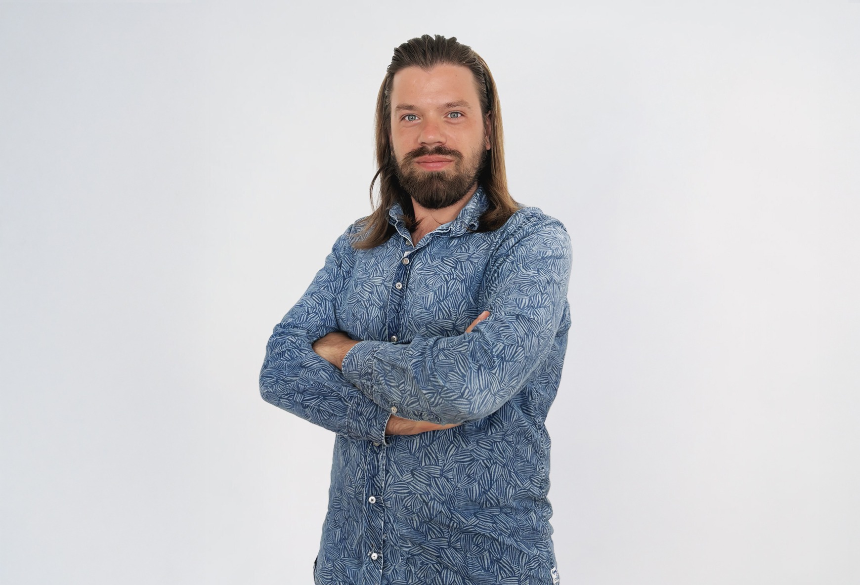 Eine Mann in einem blau gemusterten Hemd lächelt.
