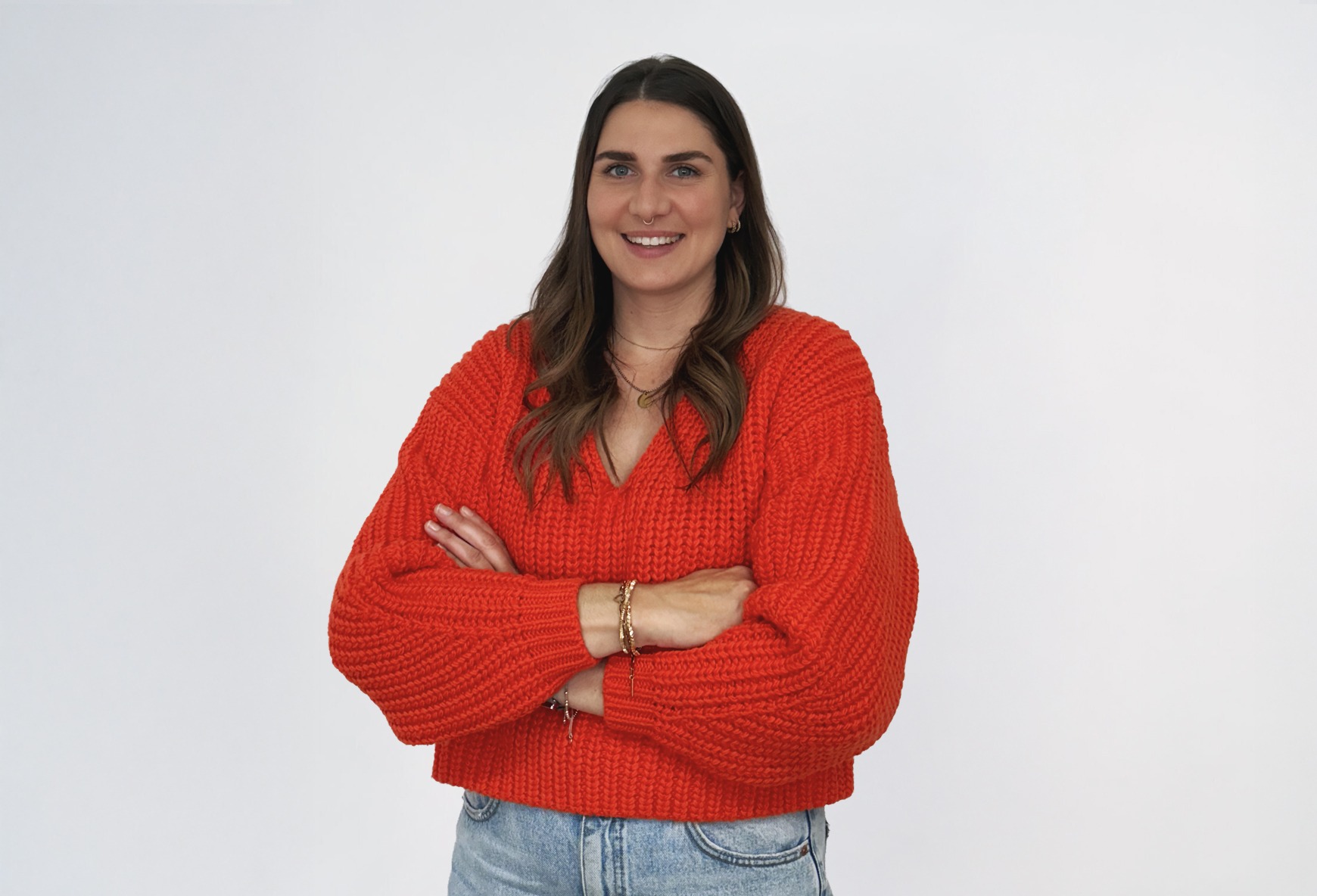 Lisa_1 Eine braunhaarige Frau in einem roten Pullover lächelt.
