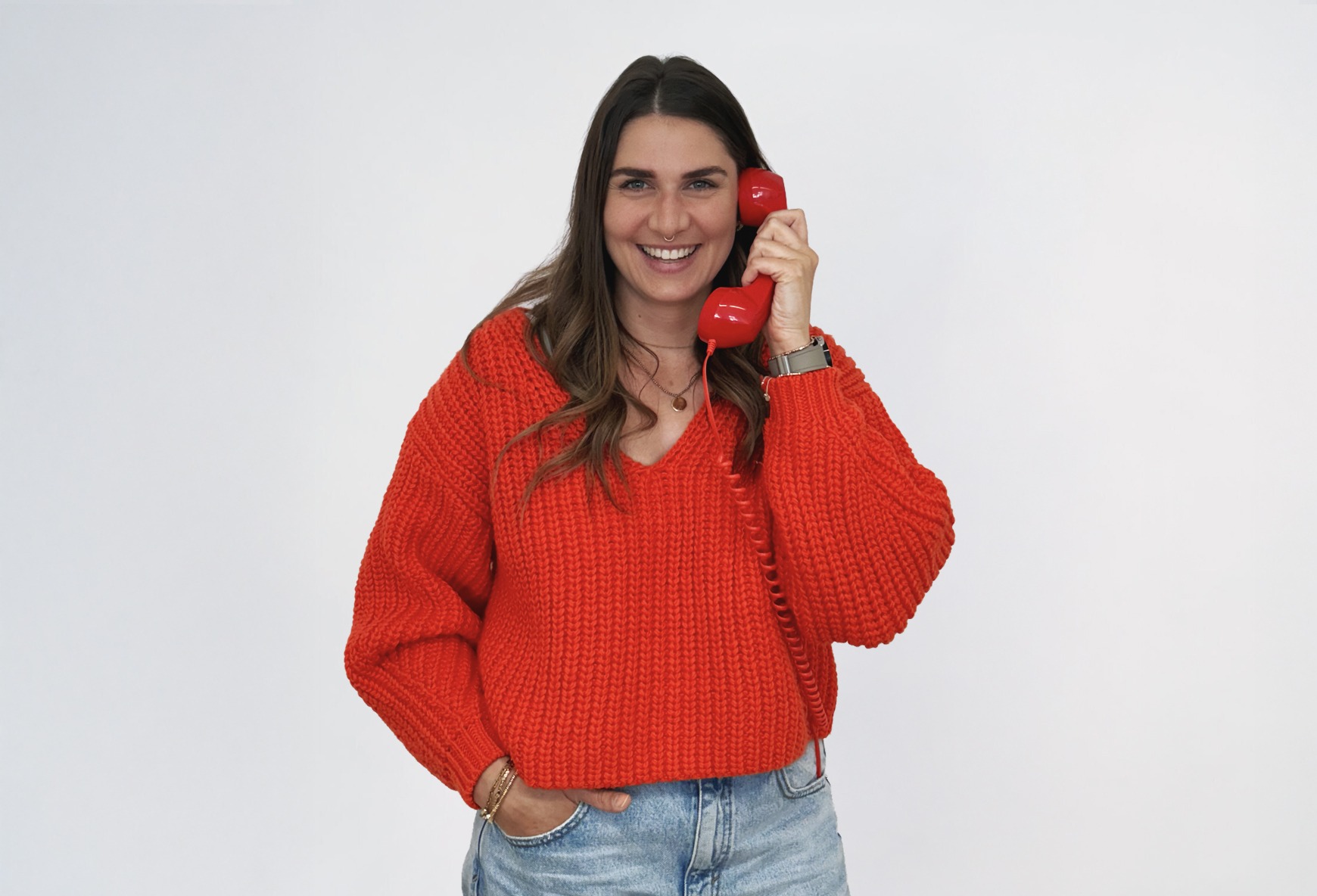 Lisa_2 Eine braunhaarige Frau in einem roten Pullover lächelt.