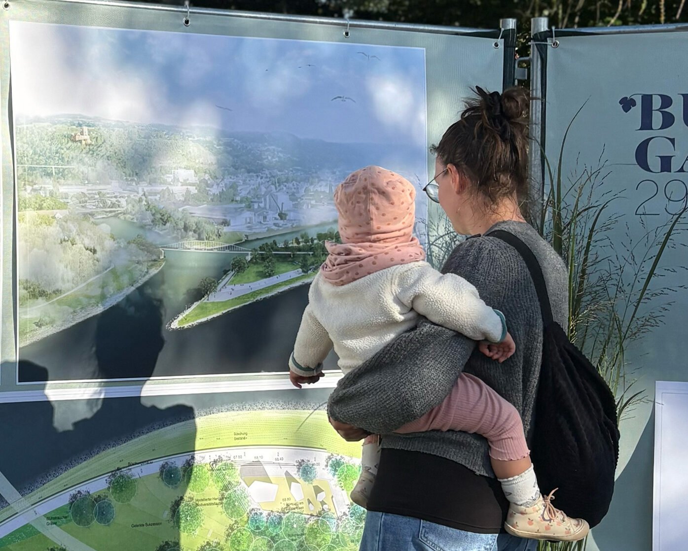 sliderimage-Eine Besucherin der BUGA-Roadshow 2025 betrachtet den Lageplan des BUGA-Parks Lahnstein